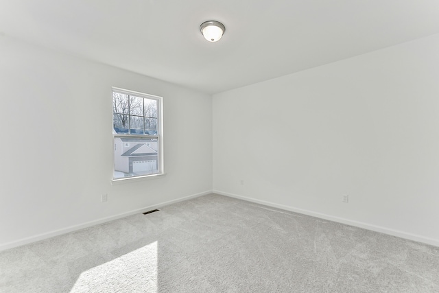 carpeted spare room featuring baseboards and visible vents