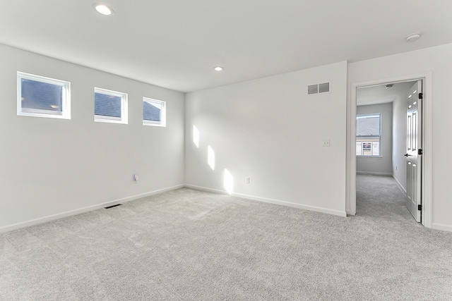 spare room with carpet floors, recessed lighting, visible vents, and baseboards