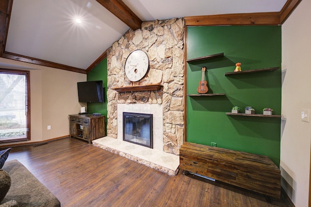 unfurnished living room featuring a fireplace, lofted ceiling with beams, ornamental molding, wood finished floors, and baseboards