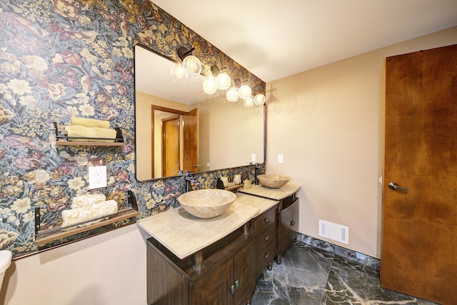 bathroom with marble finish floor, visible vents, vanity, baseboards, and wallpapered walls