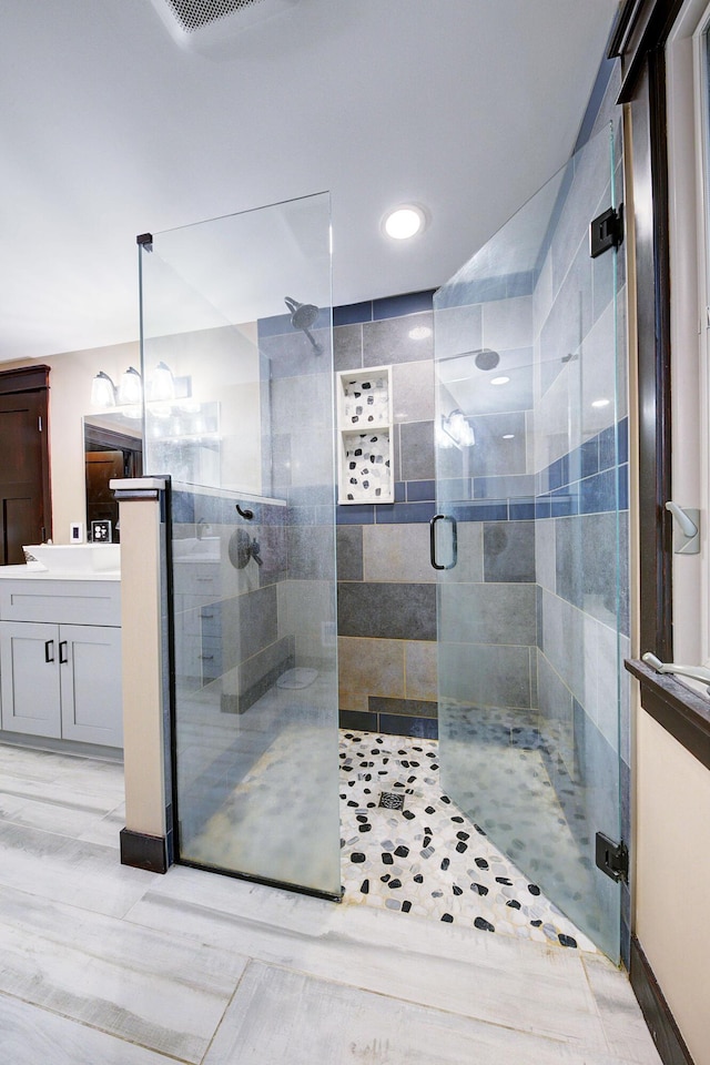 bathroom featuring visible vents, a stall shower, and vanity