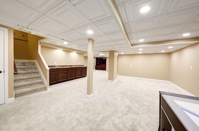 finished below grade area with stairs, baseboards, light colored carpet, and recessed lighting