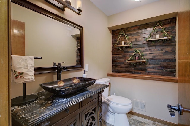 bathroom featuring toilet, vanity, and visible vents