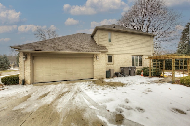 exterior space with a garage, brick siding, and roof with shingles