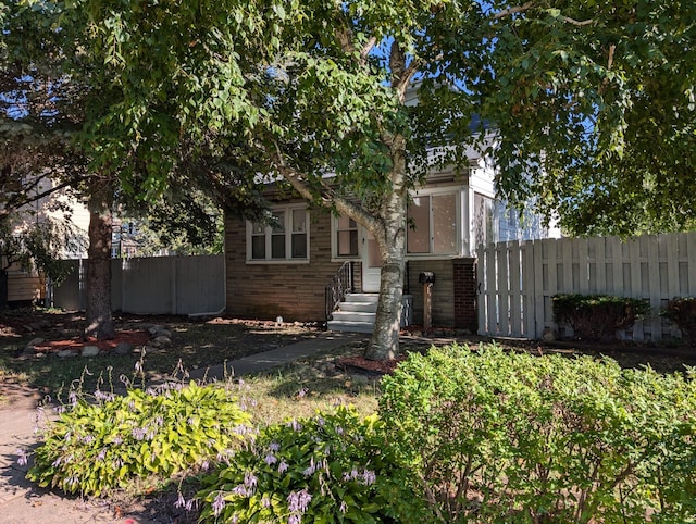 view of front facade with brick siding and fence