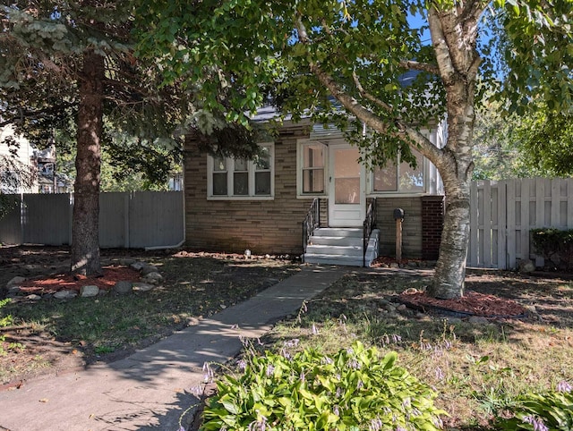 view of front facade with brick siding and fence