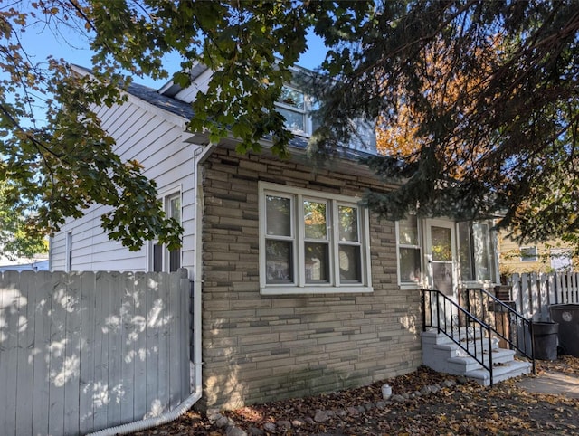 view of front of property featuring stone siding and fence