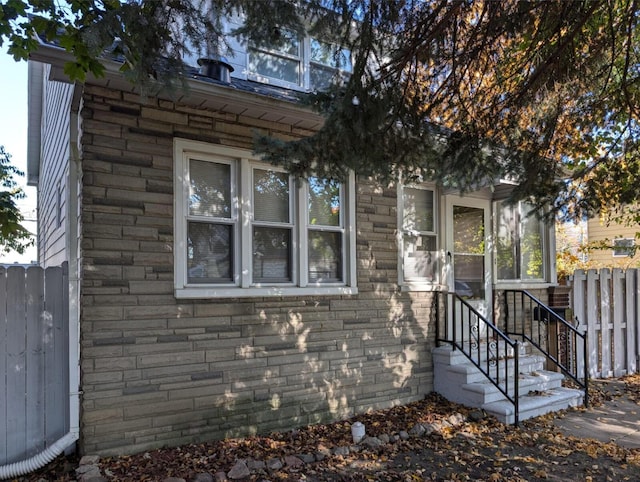 view of front of home featuring stone siding and fence