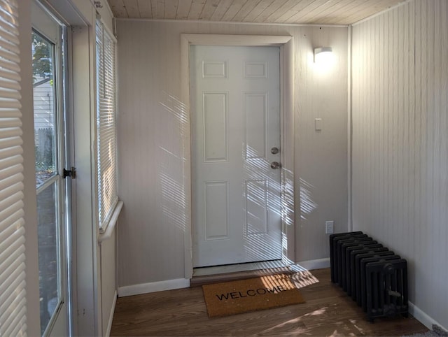 doorway with wood ceiling, radiator, baseboards, and wood finished floors