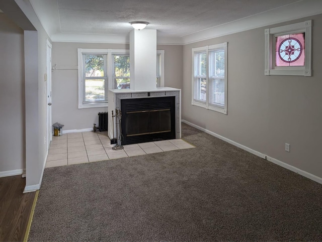 unfurnished living room with a textured ceiling, light tile patterned flooring, light colored carpet, baseboards, and a tiled fireplace