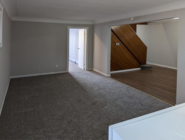 carpeted spare room featuring crown molding, stairway, and baseboards