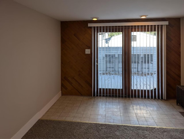 interior space with light tile patterned floors, wood walls, and baseboards