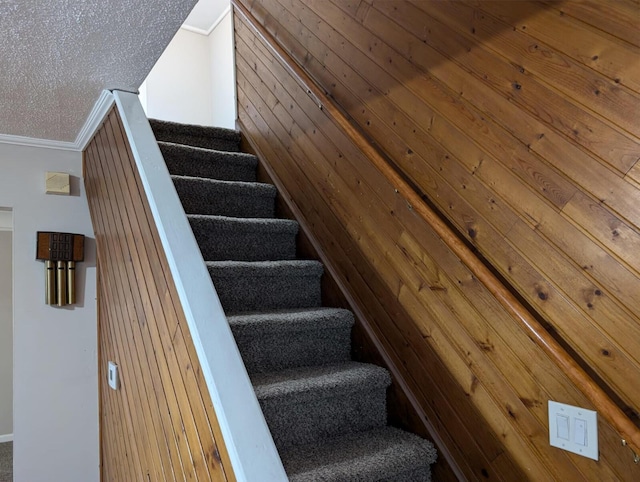 stairs featuring wood walls and ornamental molding