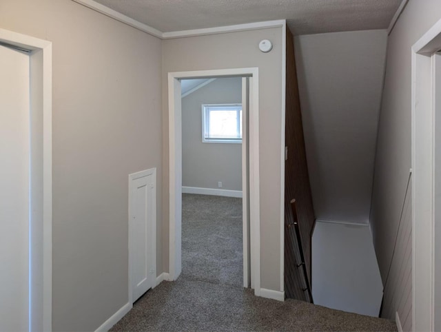 hall with carpet flooring, a textured ceiling, and baseboards