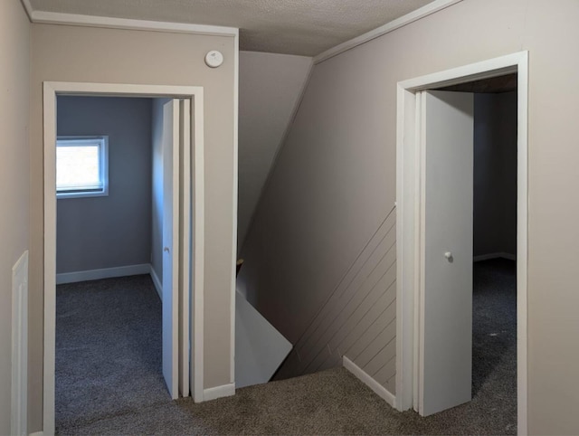 hallway with carpet flooring, a textured ceiling, and an upstairs landing