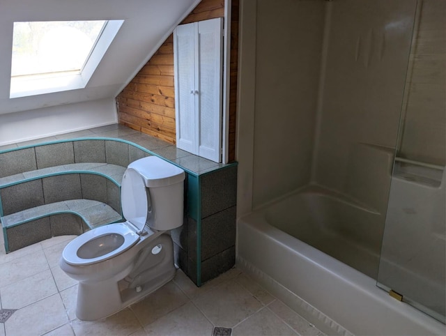 full bath featuring toilet, vaulted ceiling with skylight, and tile patterned flooring