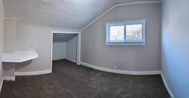 bonus room featuring lofted ceiling, dark colored carpet, and baseboards