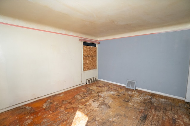 empty room featuring visible vents and hardwood / wood-style flooring