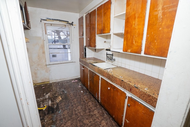 kitchen featuring tasteful backsplash, brown cabinets, a sink, and open shelves