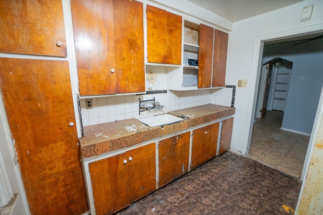 kitchen featuring open shelves, brown cabinets, a sink, and decorative backsplash