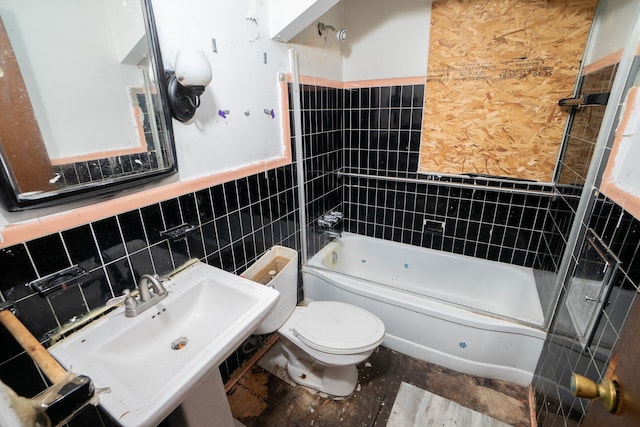 bathroom with shower / tub combination, toilet, a wainscoted wall, a sink, and tile walls