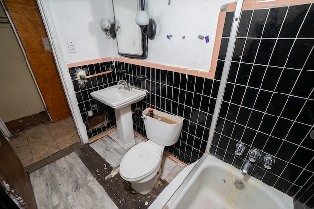 bathroom featuring wainscoting, a sink, toilet, and tile walls