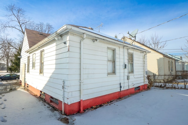 view of side of property with crawl space, roof with shingles, and fence