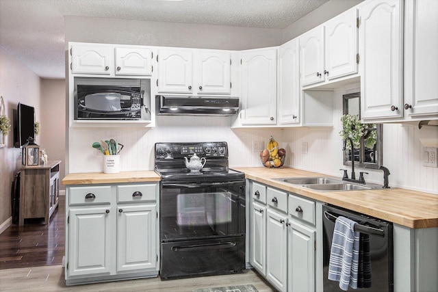 kitchen with under cabinet range hood, butcher block counters, a sink, light wood-type flooring, and black appliances