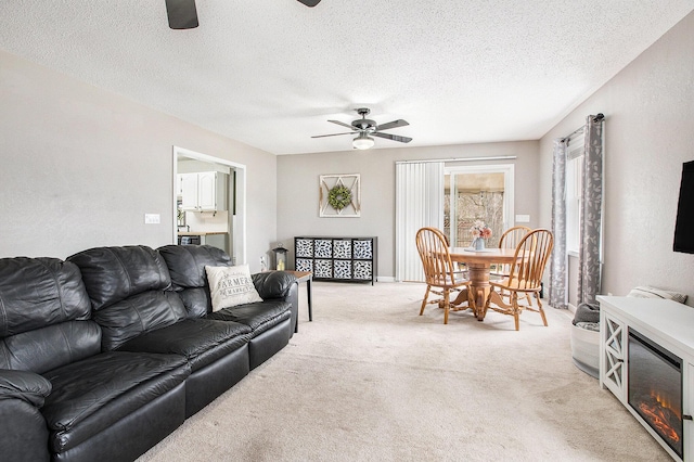 living area featuring light carpet, a textured ceiling, a ceiling fan, and a textured wall