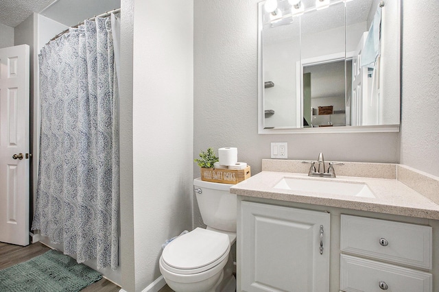 full bathroom featuring a textured wall, vanity, toilet, and wood finished floors