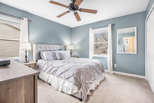 bedroom with baseboards, a closet, a ceiling fan, and light colored carpet