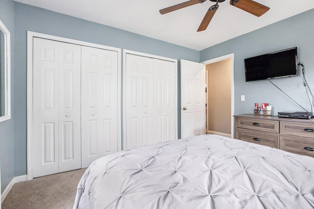 carpeted bedroom featuring baseboards, a ceiling fan, and two closets