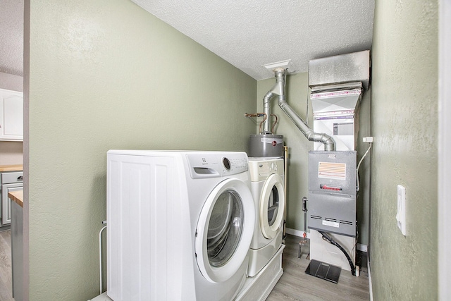 laundry room with gas water heater, light wood-style floors, a textured ceiling, washer and dryer, and laundry area