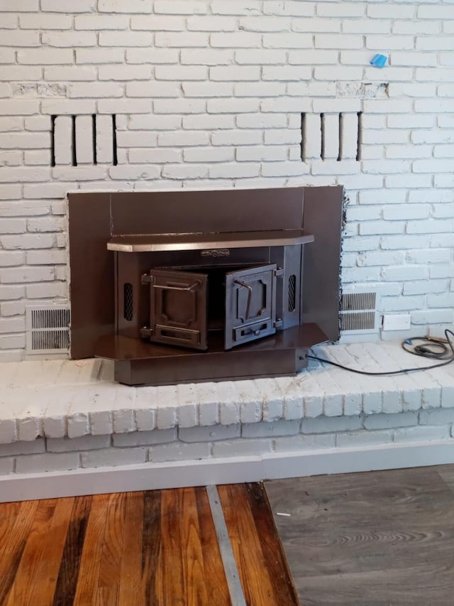 interior details with a wood stove, visible vents, and wood finished floors