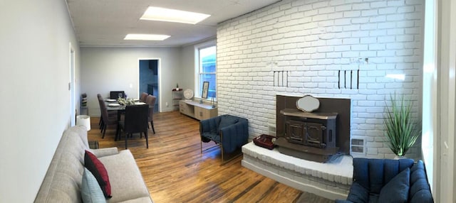 living room featuring a wood stove, brick wall, and wood finished floors