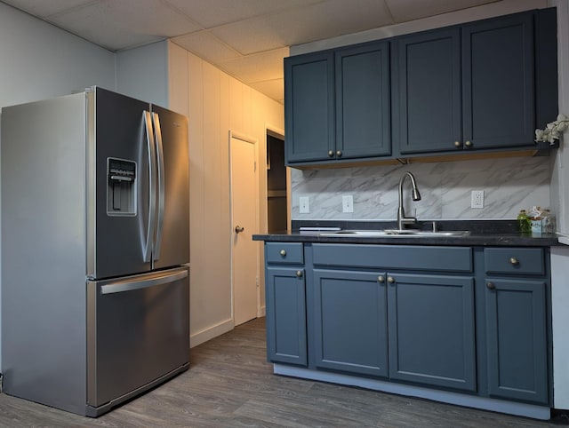 kitchen featuring a sink, blue cabinetry, dark countertops, and stainless steel fridge