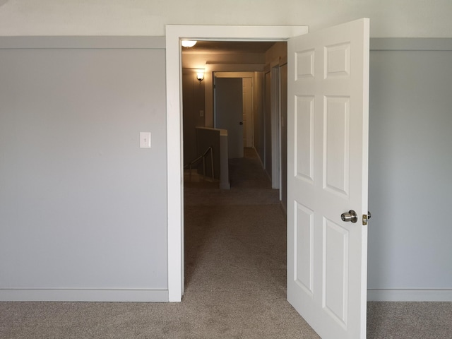 hallway with carpet floors, an upstairs landing, and baseboards