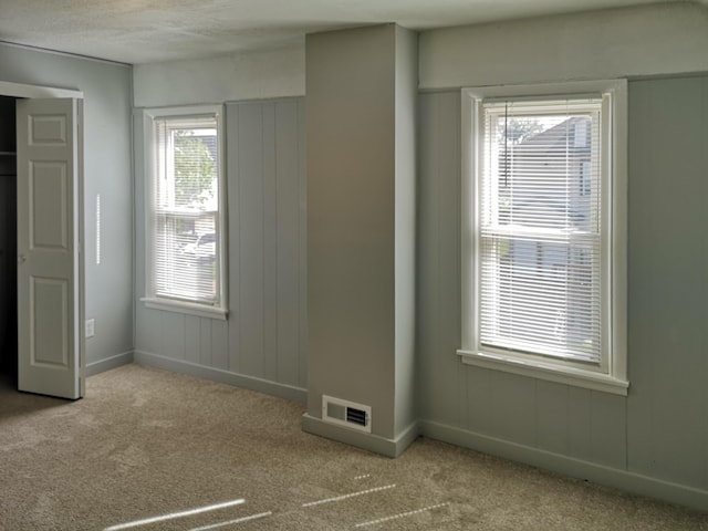 unfurnished room featuring carpet floors, baseboards, and visible vents