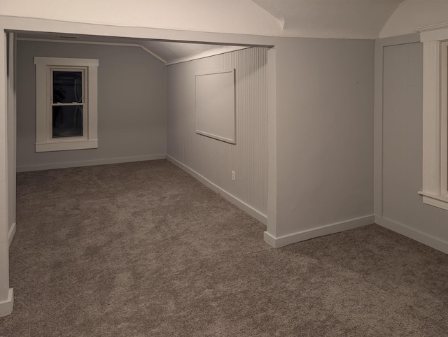 spare room featuring carpet floors, vaulted ceiling, and baseboards