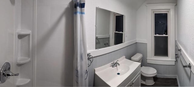 full bath featuring a shower, a wainscoted wall, toilet, vanity, and wood finished floors