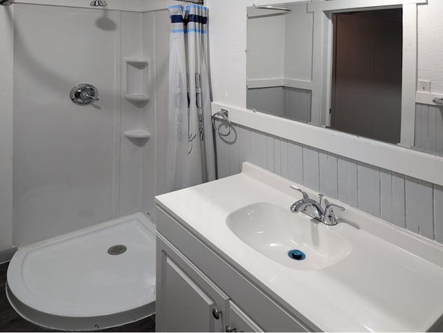 bathroom with a stall shower, wainscoting, and vanity