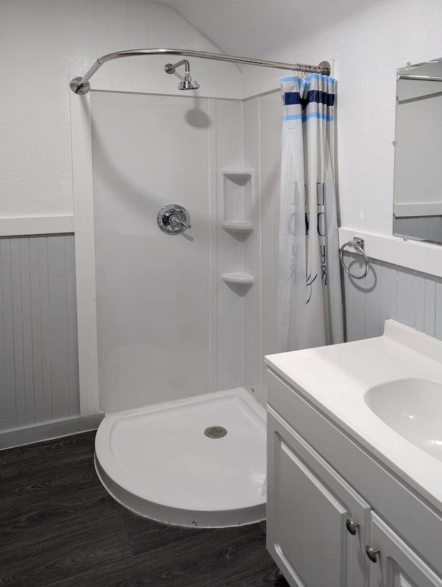 bathroom with wooden walls, wood finished floors, wainscoting, a shower stall, and radiator heating unit