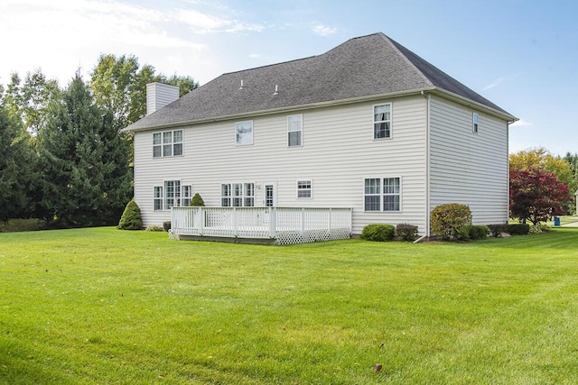 rear view of property with a deck, a yard, and a chimney