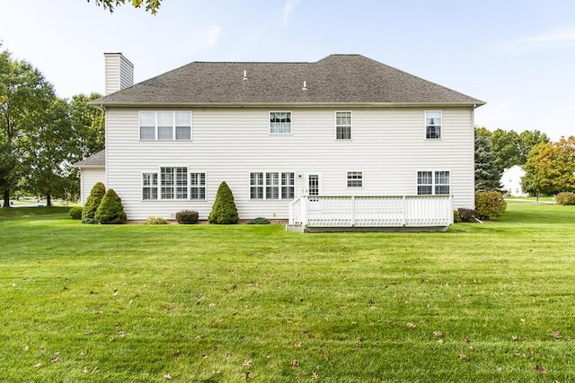 back of house with a shingled roof, a lawn, a chimney, and a wooden deck