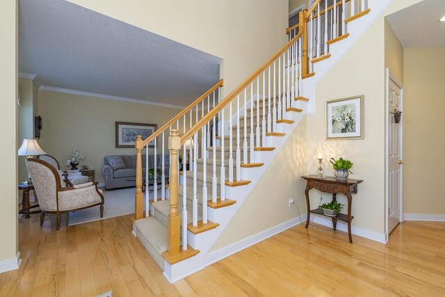 staircase featuring crown molding, baseboards, and wood finished floors