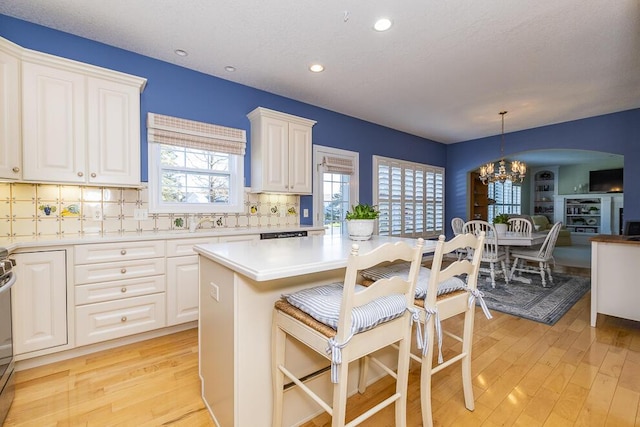 kitchen featuring tasteful backsplash, white cabinets, light wood-style flooring, and a kitchen bar