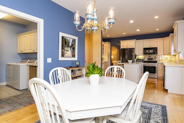 dining room with arched walkways, washer and clothes dryer, an inviting chandelier, light wood-type flooring, and recessed lighting