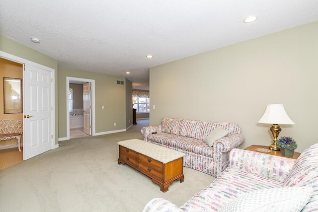 living room with a textured ceiling, recessed lighting, light colored carpet, visible vents, and baseboards