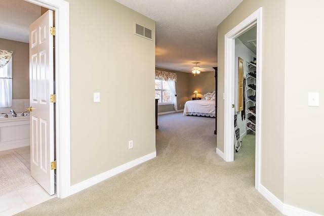 hallway featuring carpet, visible vents, and baseboards