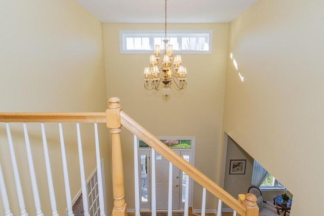 staircase featuring a towering ceiling and an inviting chandelier